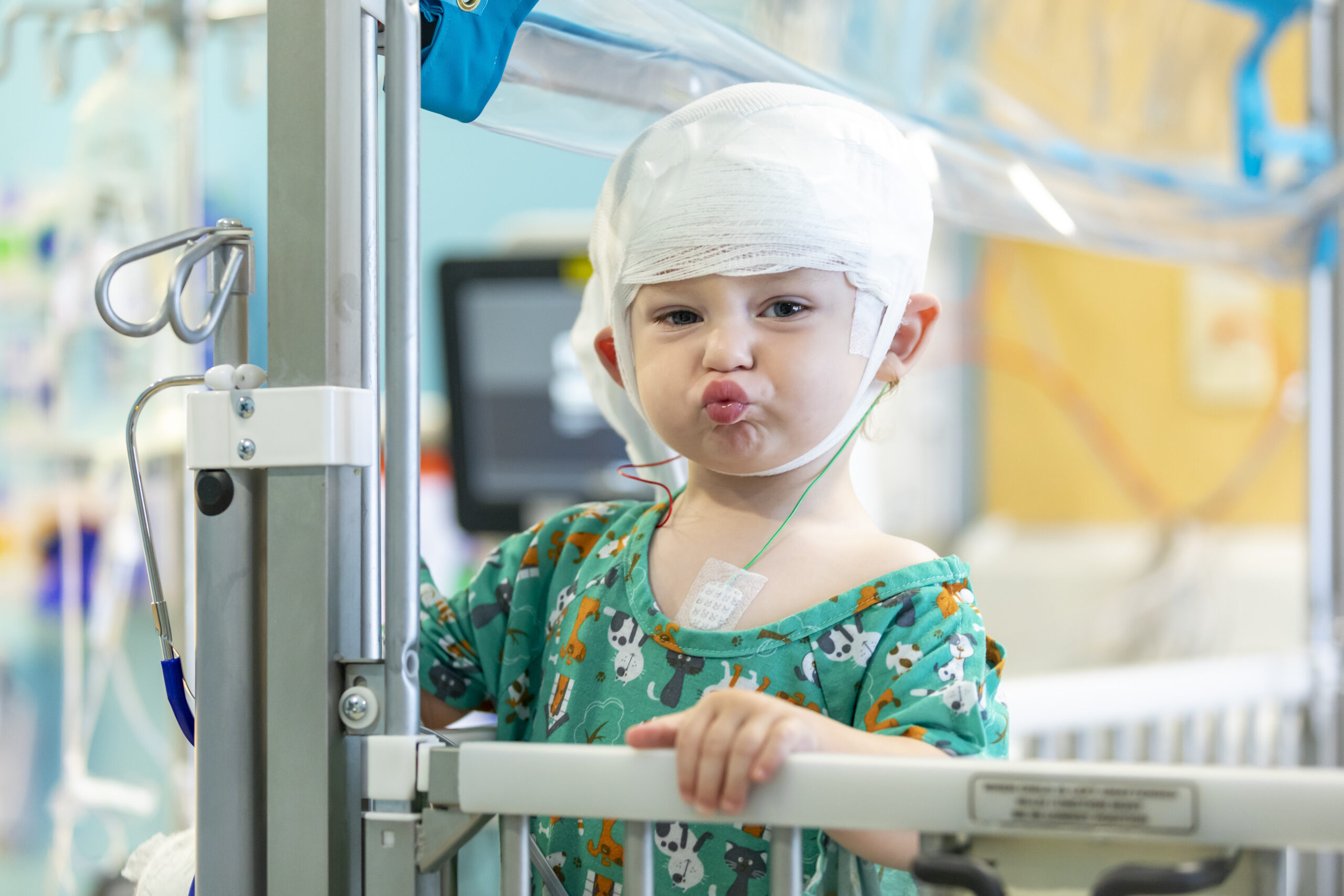 Young child in a hospital gown makes a face at the camera.