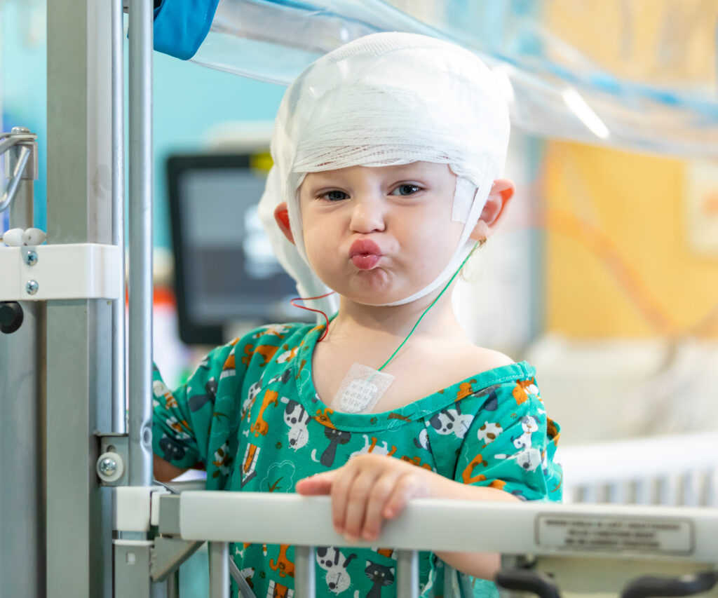 Young child in a hospital gown makes a face at the camera.